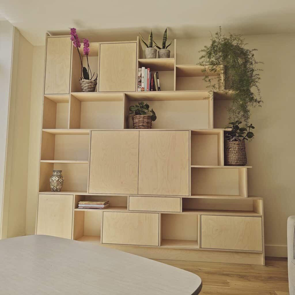 Moderne design vakkenkast op maat van eiken fineer met een speelse vakkenindeling en asymmetrische vakken. Deze handgemaakte kastenwand in de kenmerkende minimalistische Glenn Ederveen stijl is op locatie gemonteerd in een woonkamer in Delft als exclusief maatwerk interieur.